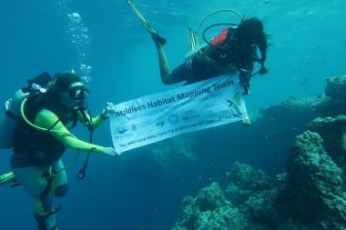 Scuba divers carrying a banner under water.